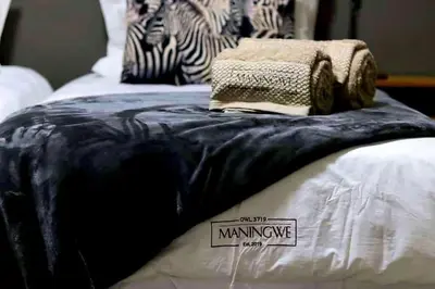 a bed with a black and white blanket on it at Maningwe in Marloth Park