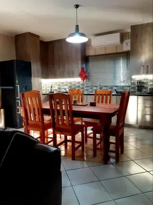 a kitchen with a wooden table and chairs and a kitchen with a refrigerator at Maningwe in Marloth Park