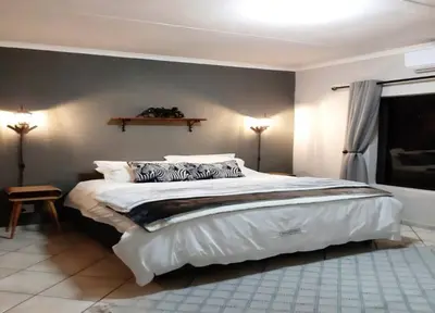 a bedroom with a large bed with white sheets and pillows at Maningwe in Marloth Park