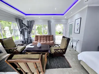 a living room with a couch and a table and chairs at Waterfall City Guest Lodge in Sandton