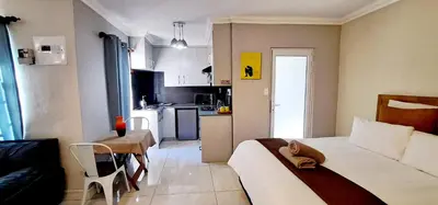 a small room with a bed and a kitchen at Waterfall City Guest Lodge in Sandton