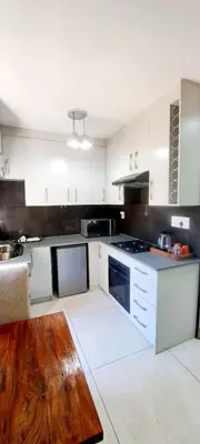 a kitchen with white cabinets and a wooden table at Waterfall City Guest Lodge in Sandton