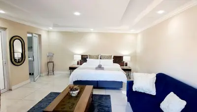 a bedroom with a bed and a blue couch at Waterfall City Guest Lodge in Sandton