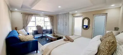 a bedroom with a large white bed and a blue couch at Waterfall City Guest Lodge in Sandton