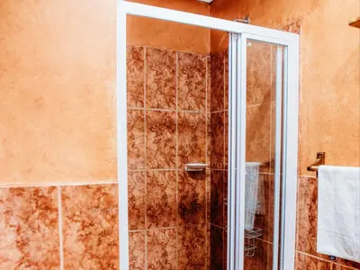 a shower with a glass door in a bathroom at Grace View Guest House in Secunda