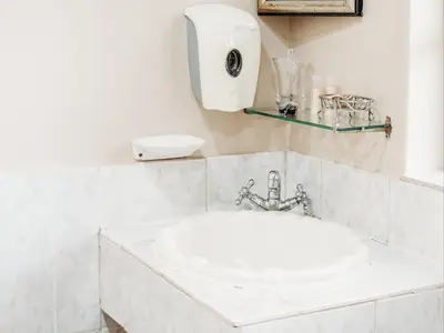 a white bathroom with a sink and a soap dispenser at Grace View Guest House in Secunda