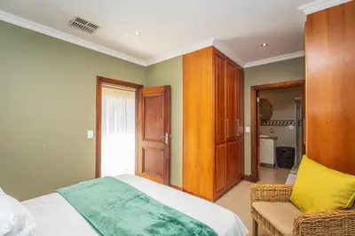 a bedroom with a bed and a chair in it at Pecanwood Retreat - Pecanwood Golf Estate - Hartbeespoort in Hartbeespoort