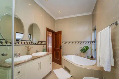 a bathroom with two sinks and two mirrors at Pecanwood Retreat - Pecanwood Golf Estate - Hartbeespoort in Hartbeespoort