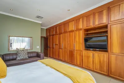 a room with a bed and a couch and a flat screen tv at Pecanwood Retreat - Pecanwood Golf Estate - Hartbeespoort in Hartbeespoort