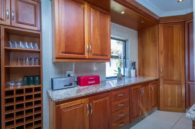 a kitchen with wooden cabinets and a red appliance at Pecanwood Retreat - Pecanwood Golf Estate - Hartbeespoort in Hartbeespoort