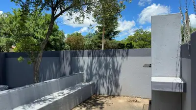 a white fence with a tree behind it at K K K Guesthouse in Secunda