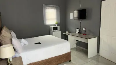 a bedroom with a bed and a desk with a microwave at K K K Guesthouse in Secunda