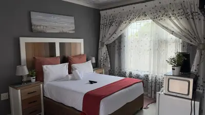 a bedroom with a bed and a window and a television at K K K Guesthouse in Secunda