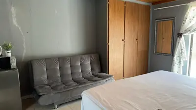 a couch sitting in a room with a bed at K K K Guesthouse in Secunda