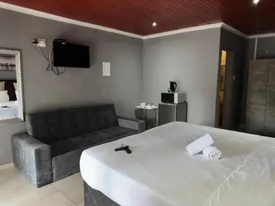 a hotel room with a bed and a couch at K K K Guesthouse in Secunda