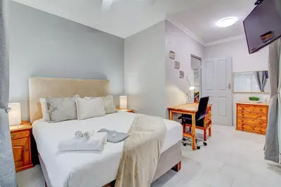 a bedroom with a bed with a desk and a computer at Luxurious self-catering villa, step-free and pet-friendly in Centurion