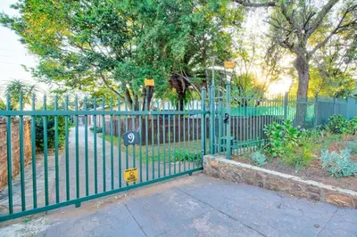 a green fence with a sign on it next to a sidewalk at Luxurious self-catering villa, step-free and pet-friendly in Centurion