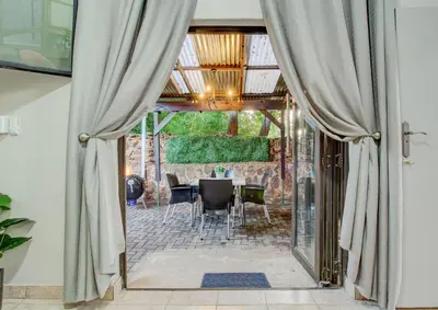 an open door to a patio with a table and chairs at Luxurious self-catering villa, step-free and pet-friendly in Centurion
