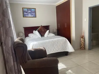 a hotel room with a bed and a chair at Sisonke Guest House in Kwamhlanga