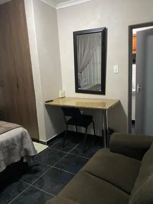 a room with a desk with a mirror and a bed at Sisonke Guest House in Kwamhlanga