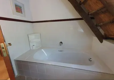 a white bath tub in a bathroom with a wooden ceiling at Blue Gum Cottage in Midrand