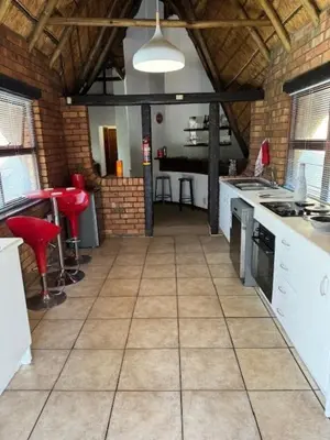 a large kitchen with white appliances and red stools at Blue Gum Cottage in Midrand