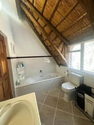 a bathroom with a bath tub and a toilet at Blue Gum Cottage in Midrand