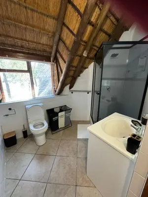 a bathroom with a toilet and a sink at Blue Gum Cottage in Midrand