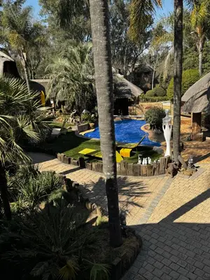 a resort with a swimming pool and palm trees at Blue Gum Cottage in Midrand