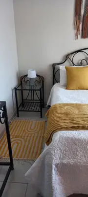 a bedroom with a bed with yellow pillows and a table at Faerie Glen, No Loadshedding, Short or Long Stays, Fast Wi-Fi in Pretoria