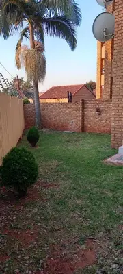 a yard with a palm tree and a brick wall at Faerie Glen, No Loadshedding, Short or Long Stays, Fast Wi-Fi in Pretoria