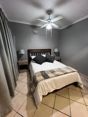 a bedroom with a bed with a ceiling fan at Lowveld Sleepover in Tzaneen