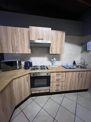 a kitchen with wooden cabinets and a stove top oven at Lowveld Sleepover in Tzaneen