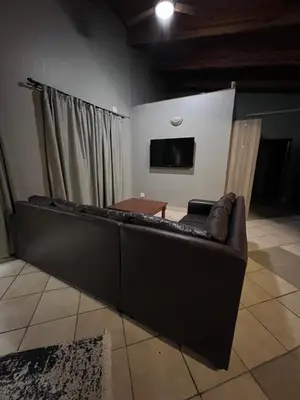 a brown couch in a living room with a tv at Lowveld Sleepover in Tzaneen
