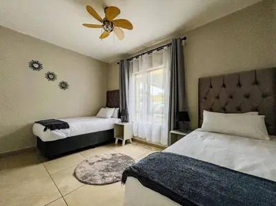 a bedroom with two beds and a ceiling fan at Self checkin - Modern Haven 2 Bedroom 43 in Nelspruit