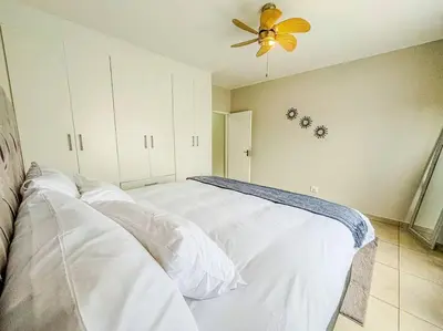 a bedroom with a white bed with a ceiling fan at Self checkin - Modern Haven 2 Bedroom 43 in Nelspruit