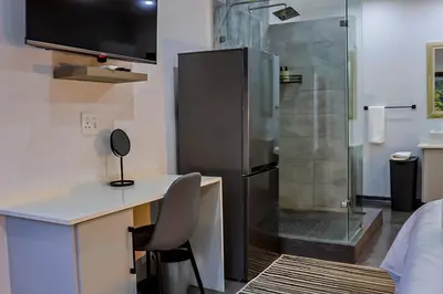a bathroom with a shower and a desk with a chair at Siesta Manor Guesthouse in Mokopane