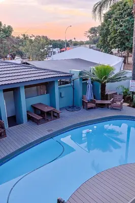 a pool with a picnic table and benches next to a house at Siesta Manor Guesthouse in Mokopane