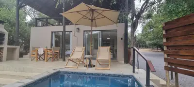 a pool with an umbrella next to a house at Buffalo Thorn Villa next to Kruger National Park in Marloth Park