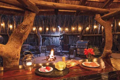 a room with a table with food and a fire at The Sanctuary in Mabalingwe Nature Reserve in Mabula