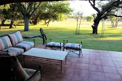 a patio with a couch and two chairs and a table at The Sanctuary in Mabalingwe Nature Reserve in Mabula