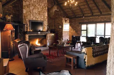 a living room with a fireplace and leather chairs at The Sanctuary in Mabalingwe Nature Reserve in Mabula