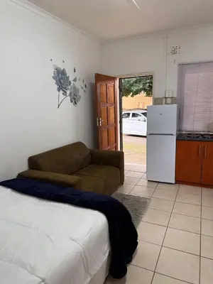 a living room with a couch and a kitchen at Aviation Stay in Kempton Park