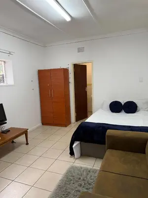 a bedroom with a bed and a couch and a television at Aviation Stay in Kempton Park
