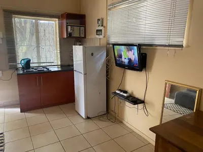 a kitchen with a refrigerator and a tv on the wall at Aviation Stay in Kempton Park
