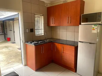 a kitchen with wooden cabinets and a white refrigerator at Aviation Stay in Kempton Park