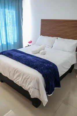 a large bed with a blue and white blanket on it at Bonnie house in Crocodile Valley Estates