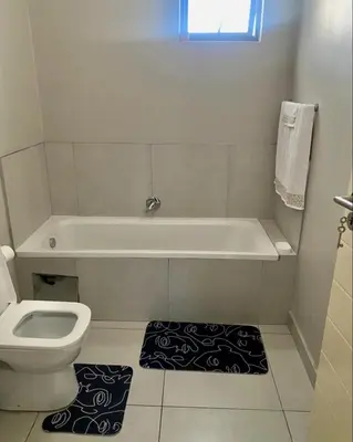a bathroom with a tub and a toilet and a rug at Ladybug ladybug in Midrand