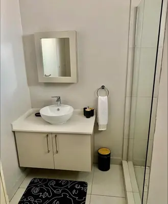 a white bathroom with a sink and a shower at Ladybug ladybug in Midrand
