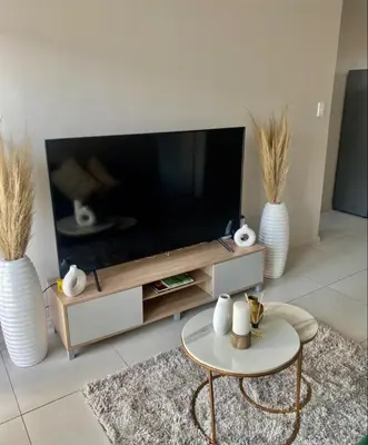 a living room with a flat screen tv and two white vases at Ladybug ladybug in Midrand